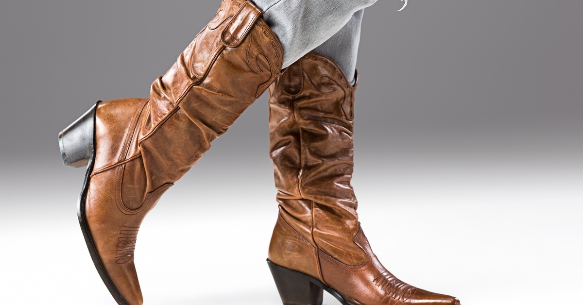 Boot Styles Every Western-Loving Girl Needs The legs of a woman in pale-gray ripped jeans and brown snip-toe boots with a white-and-gray ombré background.