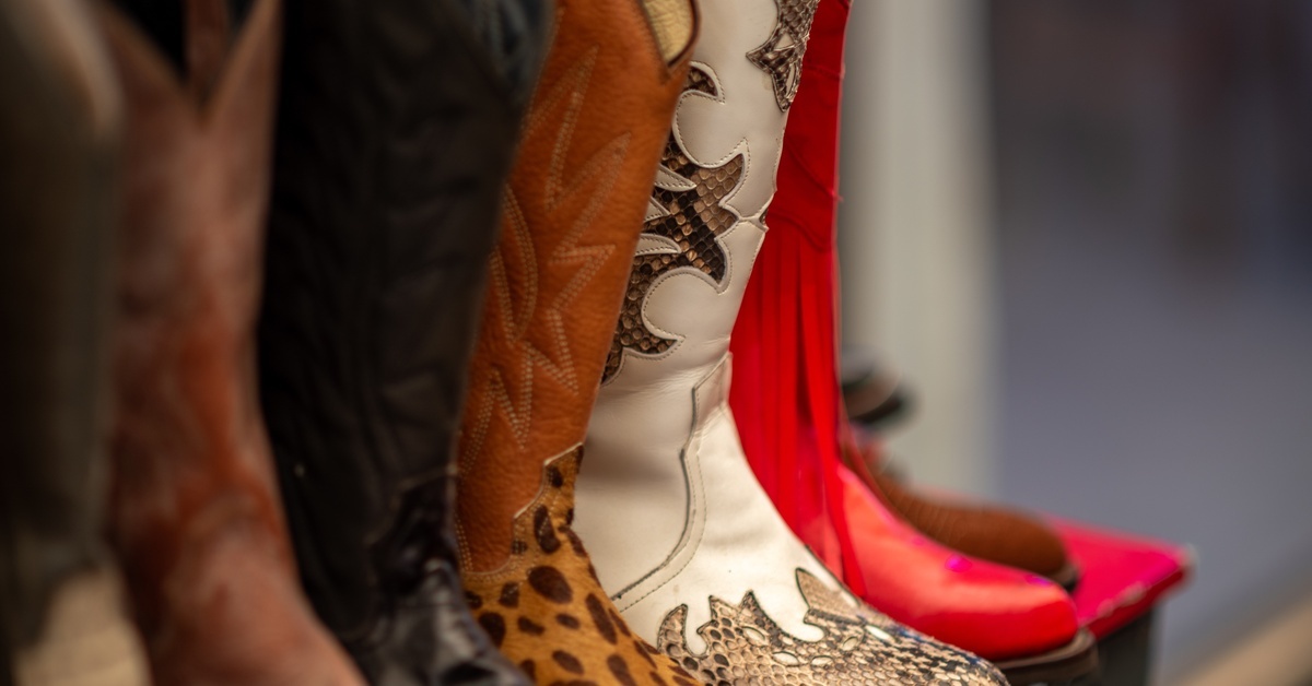 A collection of cowboy boots in different styles, from red and fringed to classic brown leather with a cheetah patterned sole.