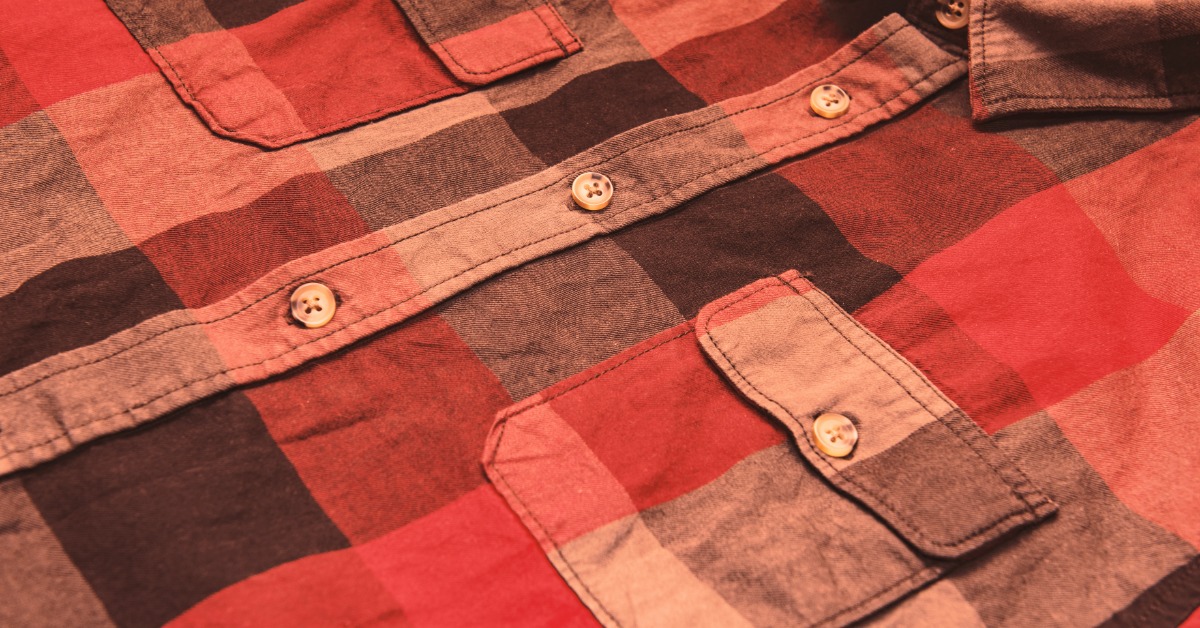 A slightly wrinkled checkered shirt with a monochromatic red color scheme laid out flat on a surface.