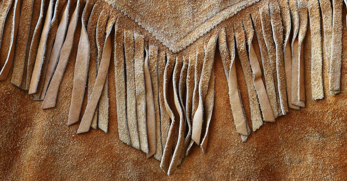A close up of fringe details on vintage leather showing layered strips and textured material in soft focus.