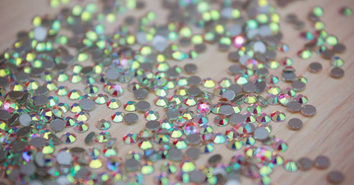 A close up of shiny rhinestones arranged closely together on a table with light reflecting across them.