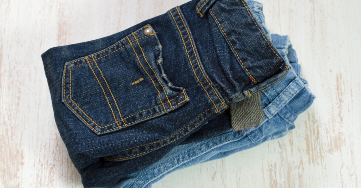 Two pairs of folded baby jeans, one in a darker wash, the other in a lighter wash, stacked on top of each other.