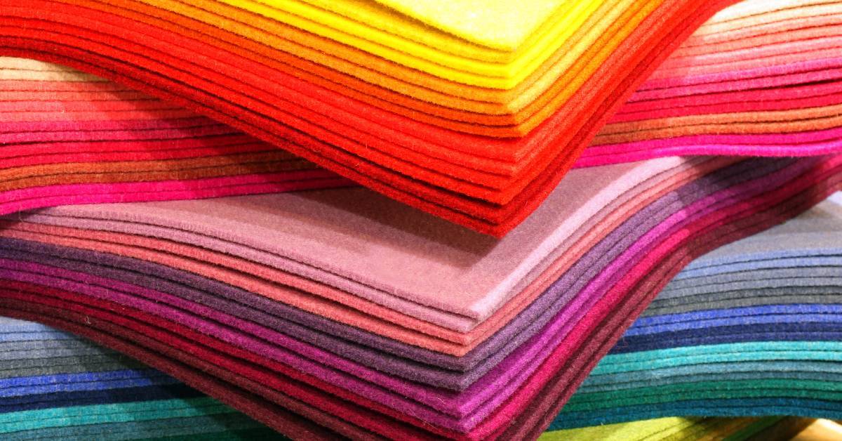 A display of colored felt fabric pieces stacked and arranged in rows inside a shop with multiple shades visible.