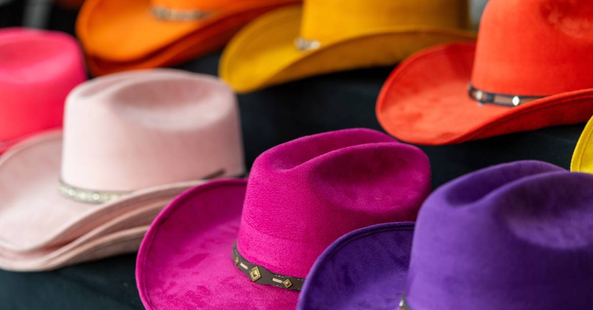 A group of colorful felt cowboy hats arranged on a table with bright tones and bands visible around each crown.