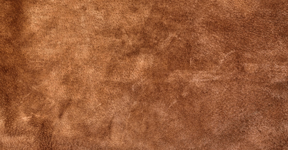 A close-up of smooth brown suede leather texture with subtle grain and seamless material surface details.