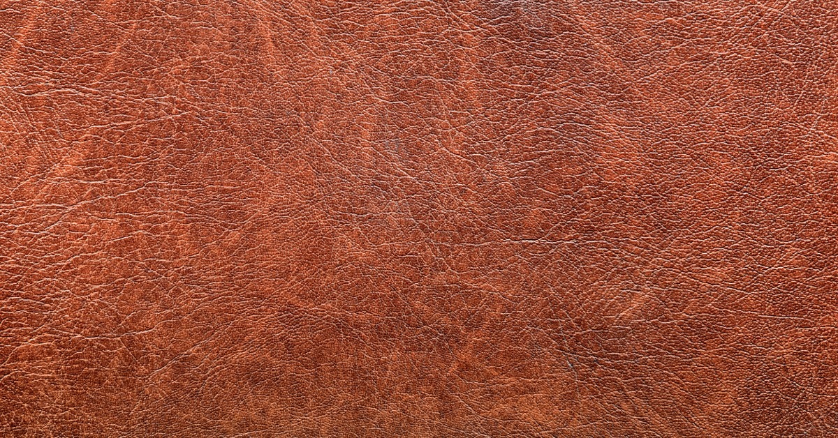 A red vintage leather background with aged grunge texture, worn surface marks, and dark mottled color.